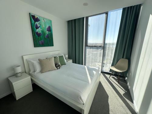 een slaapkamer met een wit bed en een groot raam bij Lake Views Belconnen in Belconnen