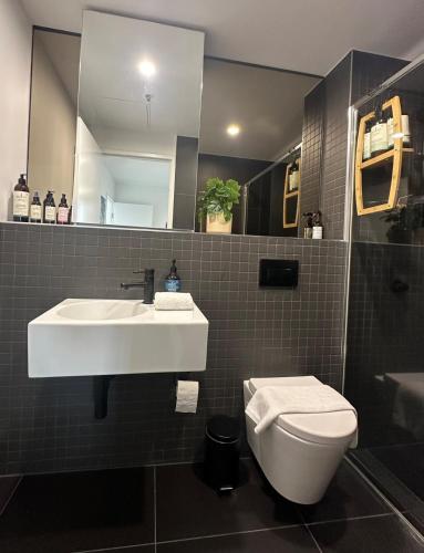 a bathroom with a sink and a toilet and a mirror at Lake Views Belconnen apartment with 2 bedrooms and sofa bed in Belconnen