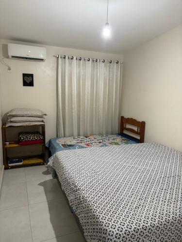 a bedroom with a bed and a window with a curtain at Pousada Paraíso Central - Casinha in Rodeio