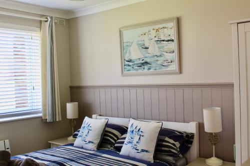 a bedroom with a bed with blue and white pillows at Driftwood Heart in Freshwater