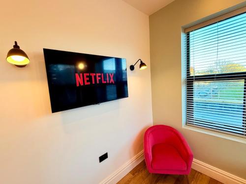 a red chair in a room with a tv on the wall at Central - Free parking- Sleeps 6 - Stylish Apt in Bristol