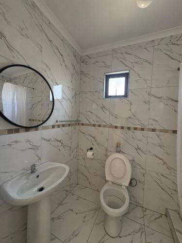 a bathroom with a sink and a toilet and a mirror at Suuka Guest House in Walvis Bay