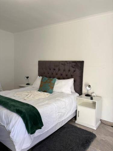 a bedroom with a white bed with a green blanket at Suuka Guest House in Walvis Bay