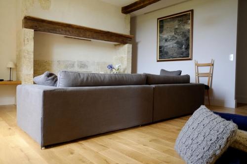 een bruine bank in een woonkamer met een houten vloer bij Maison Breton in Biran