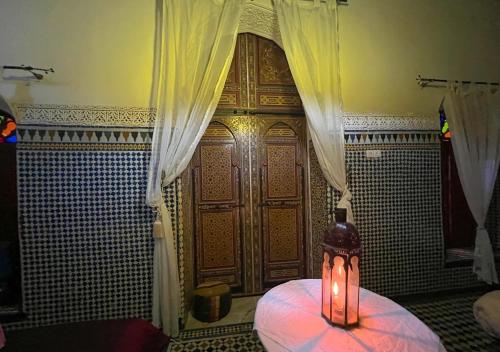 a room with a large wooden door with a candle at Riad Iman in Fès