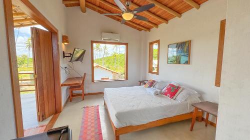 a bedroom with a bed and a window and a desk at Vila Budião - Corumbau in Corumbau
