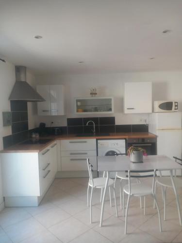 eine Küche mit einem Tisch und Stühlen darin in der Unterkunft Appartement avec jardin in Servian