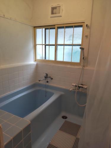 a bathroom with a blue tub and a window at 103個室元芸者の隠れ宿湯河原 in Yugawara