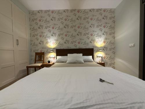 a bedroom with a large white bed with floral wallpaper at The White House in Calafell