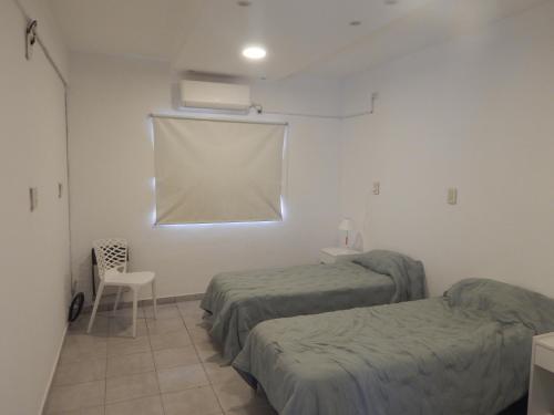 a room with two beds and a window and a chair at San Cayetano in Paraná