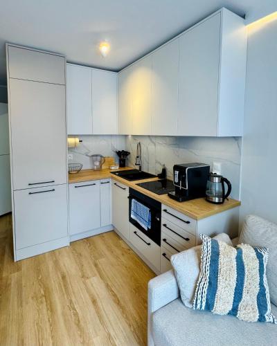 a kitchen with white cabinets and a couch at Modrzewiowa Przygoda in Debina