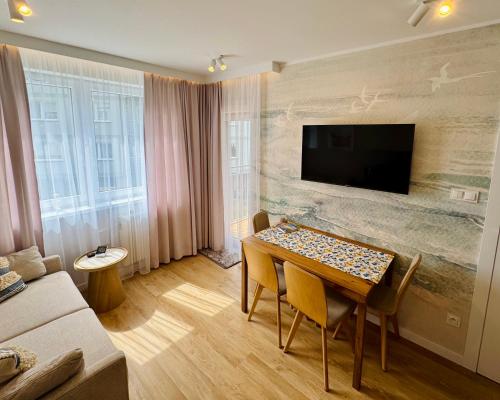 a living room with a table and a tv on a wall at Modrzewiowa Przygoda in Debina