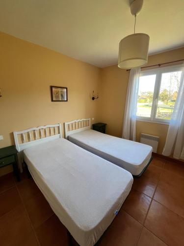 zwei Betten in einem Zimmer mit Fenster in der Unterkunft Maison chaleureuse in Mézos