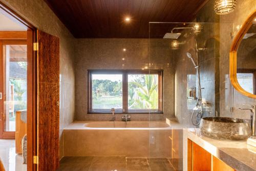 a bathroom with a tub and a sink and a window at Bagus Bandem Villa in Ubud