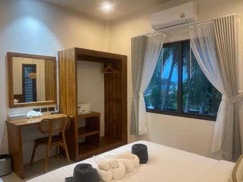 a bedroom with a bed with a desk and a window at Breeze Bay Villas Koh Phangan in Wok Tum