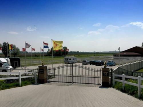 a gate with cars parked in a parking lot with flags at Appartement Gio in Strijen