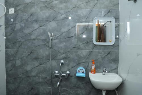a bathroom with a sink and a mirror and a shower at VAISHVI Homestay in Kāsarkod