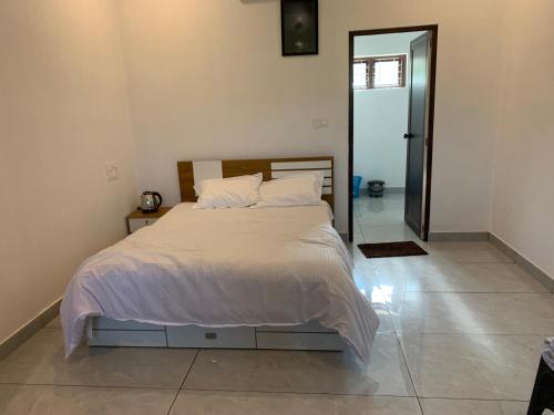 a bedroom with a large bed with white sheets and pillows at Elysian in Mananthavady