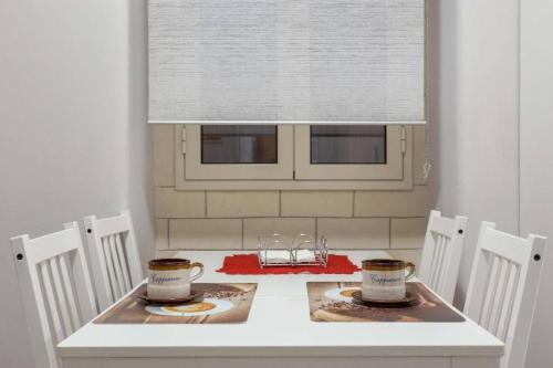 卡塔尼亚Two Rooms Bellini的一张白色桌子，上面放着两个杯子、几把椅子和一扇窗户。