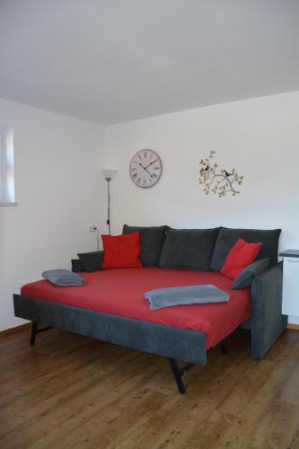 a couch with red pillows and a clock on the wall at Appartement Wieshof in Neukirchen am Großvenediger