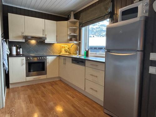 een keuken met witte kasten en een roestvrijstalen koelkast bij Leilighet Ski in/out, golf in Vradal