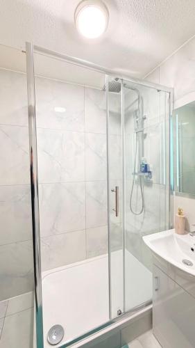 a shower with a glass door in a bathroom at Modern 1 bed super fast WiFi in Brentford