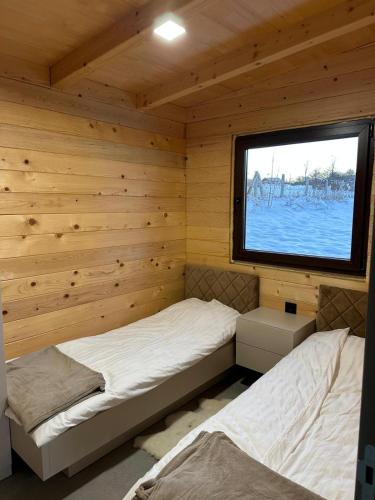 two beds in a log cabin with a window at Suncatcher Djurdjevic Apartmani in Banja Luka