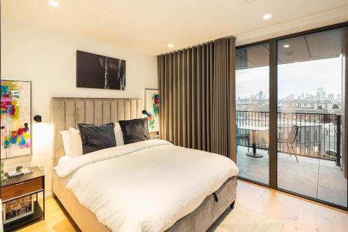 a bedroom with a large bed and a balcony at Stylish 1BR Escape - Gym -Balcony - Lift in London