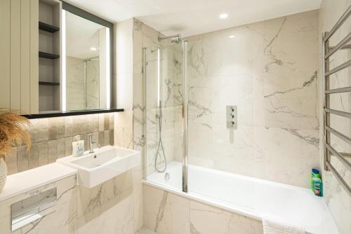a bathroom with a tub and a sink and a shower at Stylish 1BR Escape - Gym -Balcony - Lift in London