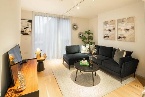 a living room with a black couch and a table at Stylish 1BR Escape - Gym -Balcony - Lift in London