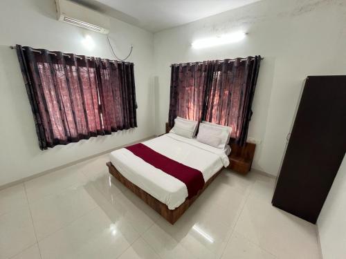 a small bedroom with a bed and two windows at Aarna Villa nr Valvan Dam in Lonavala