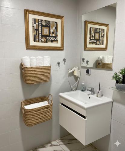 a bathroom with a white sink and baskets on the wall at Azra Homes Famille uniquement in Saïdia