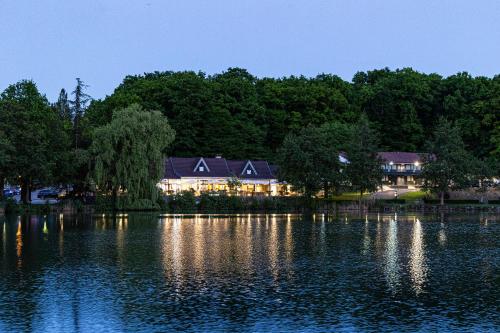 a house on the shore of a lake at night at LaCorniche Hôtel in Contrexéville