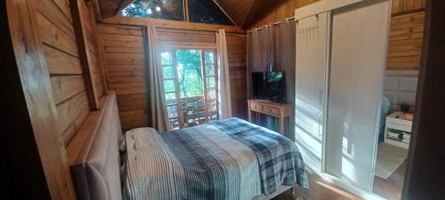 een slaapkamer met een bed en een televisie in een hut bij Birds' Corner Cabin in Curitiba