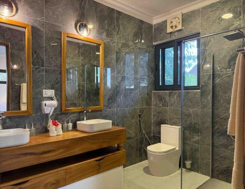 a bathroom with two sinks and a toilet and a shower at MANOLO Beach Resort in Uroa