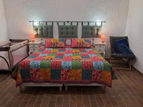 a bedroom with a bed with a colorful quilt at Le Chaumois, CHAUM 31440 in Chaum