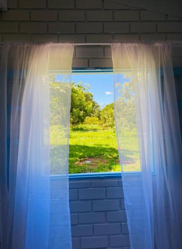 una finestra con vista su un campo verde di Casa Das Flores Piri a Pirenópolis