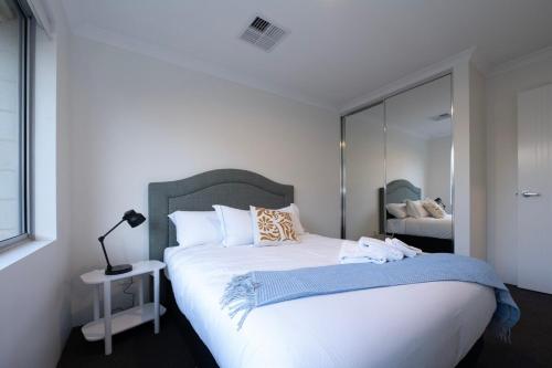 a bedroom with a large white bed with a mirror at Henley Brook - Finest in Henley Brook