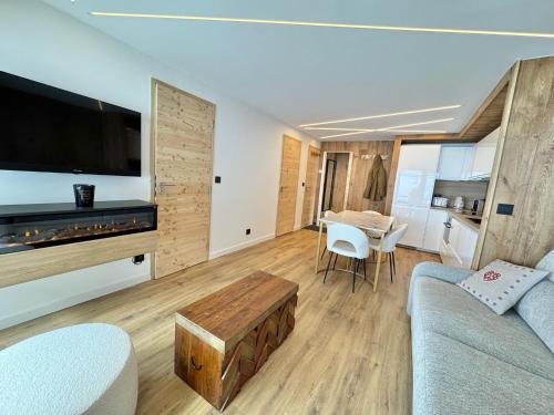ein Wohnzimmer mit einer Couch, einem Fernseher und einem Tisch in der Unterkunft T3 sur les pistes - Les Claux in Vars