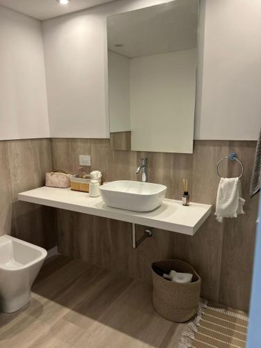a bathroom with a sink and a toilet and a mirror at Departamento BOSQUE - Unidad 218 in Costa del Este