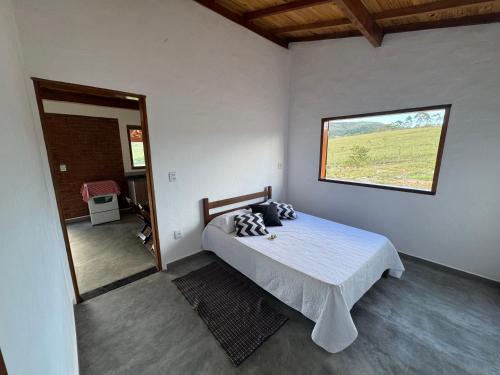een slaapkamer met een bed in een kamer met een raam bij Sítio Vista da Serra - Carrancas in Carrancas