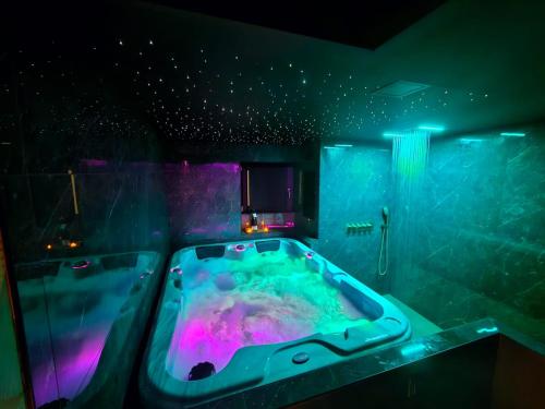 een badkamer met een badkuip met paarse en groene verlichting bij La secrète room in La Mure
