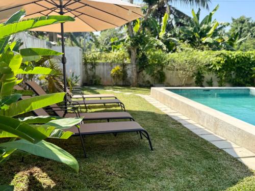 een groep stoelen met een parasol naast een zwembad bij Villa Carla Mirissa in Mirissa