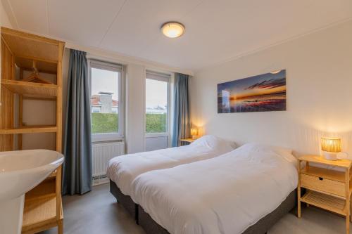 une chambre avec un lit blanc et un lavabo dans l'établissement Koudenburgweg 36, à Hollum
