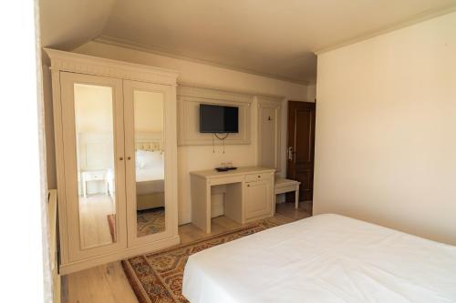 a white bedroom with a bed and a tv at Hanul Mariei in Livezile