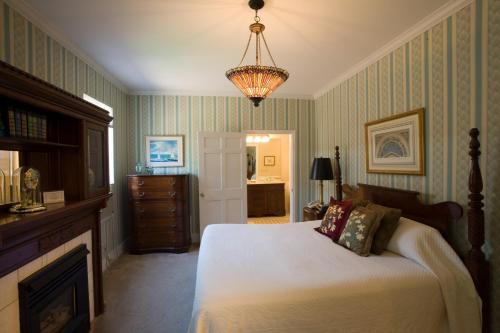a bedroom with a bed and a fireplace and a chandelier at Maplewood Hotel in Saugatuck