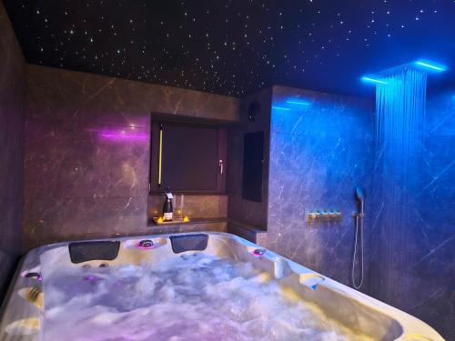 a bathroom with a bath tub with purple lights at Suite romantique avec jaccuzzi - proche des lacs - La secrète room in La Mure