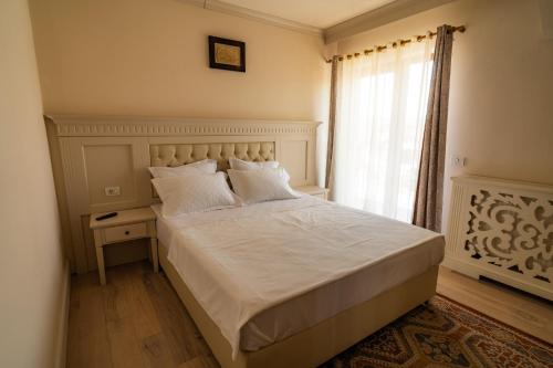 a bedroom with a bed with white sheets and a window at Hanul Mariei in Livezile