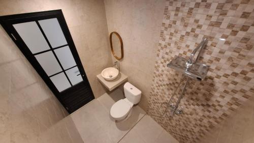 a bathroom with a toilet and a sink and a mirror at Kalih Rooms in Ubud