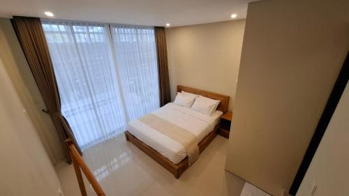 a small bedroom with a bed and a large window at Kalih Rooms in Ubud